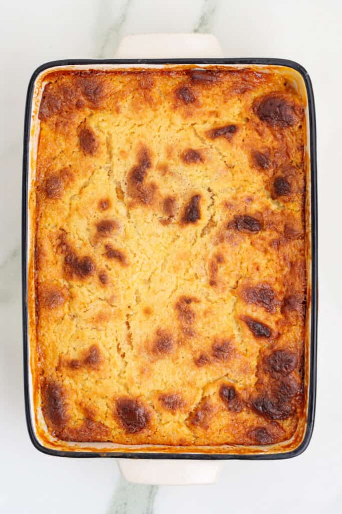 Baked golden brown Piña Colada Bread Pudding just out of the oven in a white rectangular dish