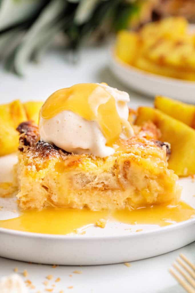 Front view of Piña Colada Bread Pudding with ice cream and grilled pineapple on a white plate
