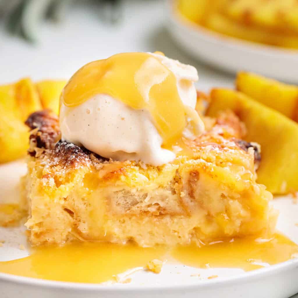 Square-cropped image of Piña Colada Bread Pudding with vanilla ice cream and golden sauce