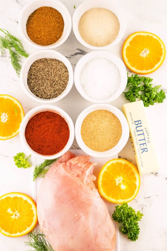 Ingredients for smoked Cajun turkey breast with boneless turkey breast, butter, fresh herbs, Cajun seasoning, smoked paprika, garlic, onion, salt, and pepper