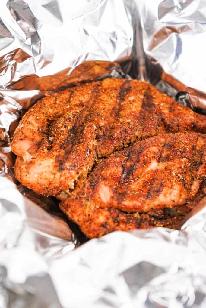 Smoked Cajun turkey breast resting in aluminum foil after cooking