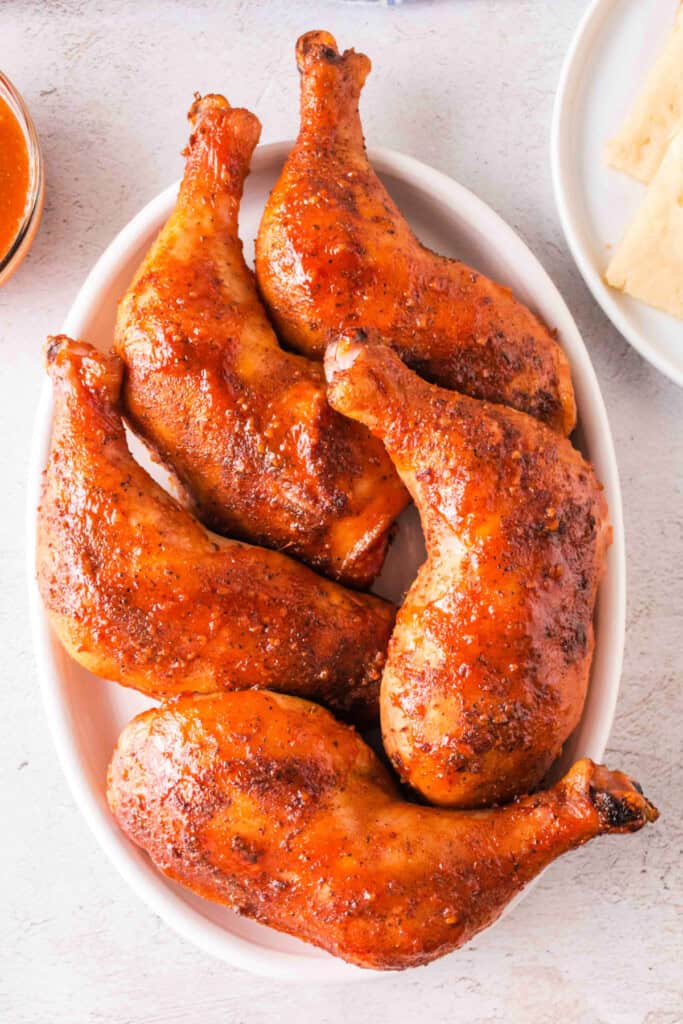 Finished smoked chicken quarters served in a white oval dish