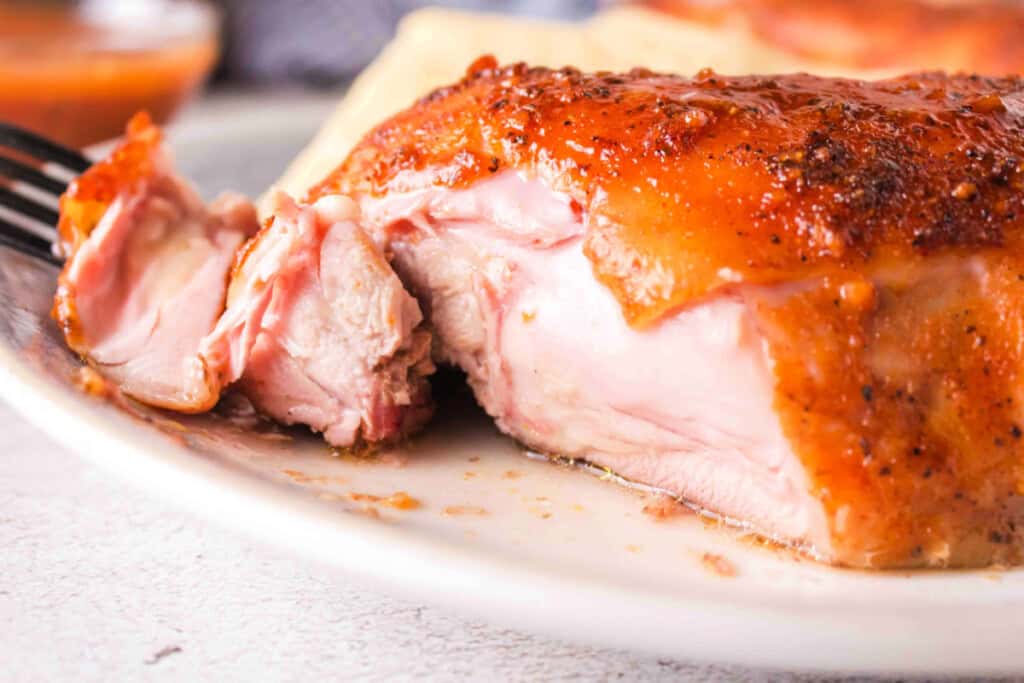 Closeup of juicy smoked chicken leg quarter cut open on a plateCloseup of juicy smoked chicken leg quarter cut open on a plate
