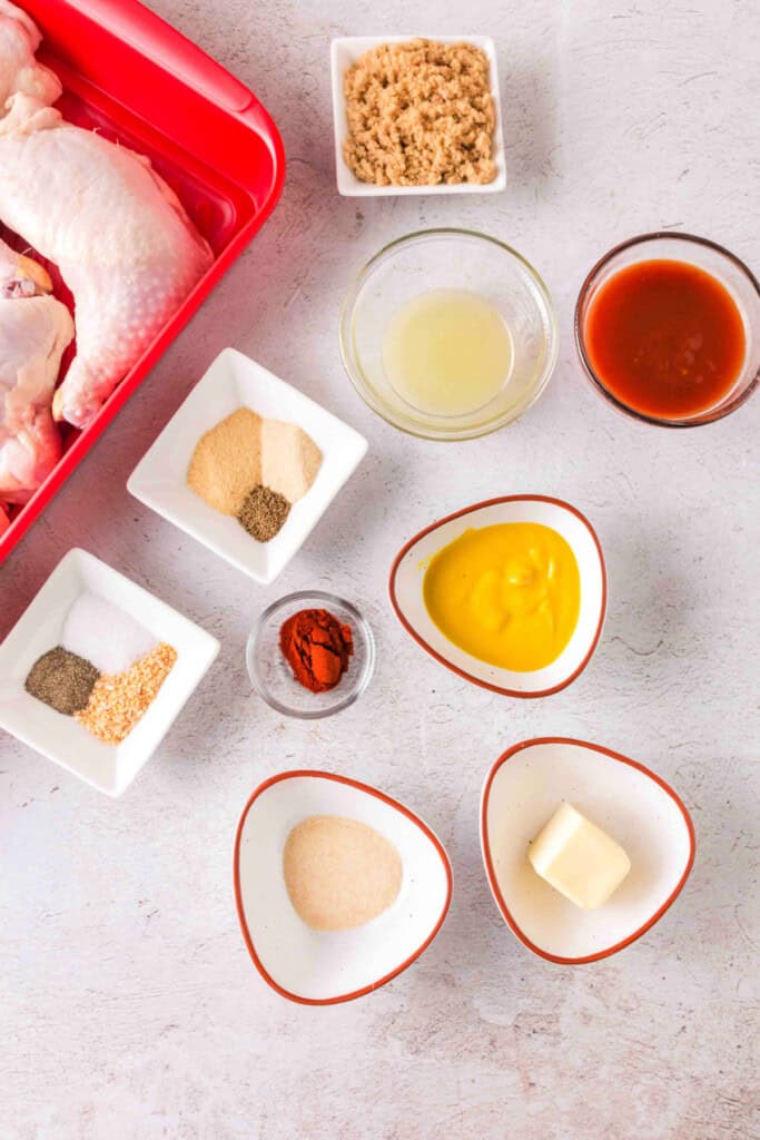 Overhead view of raw chicken quarters with seasonings and glaze ingredients