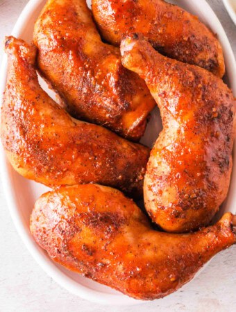 Top-down view of glazed smoked chicken leg quarters arranged in a dish