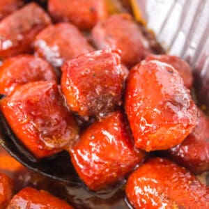 Close-up of caramelized hot dog burnt ends in BBQ sauce, scooped from the pan
