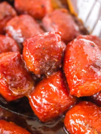Close-up of caramelized hot dog burnt ends in BBQ sauce, scooped from the pan