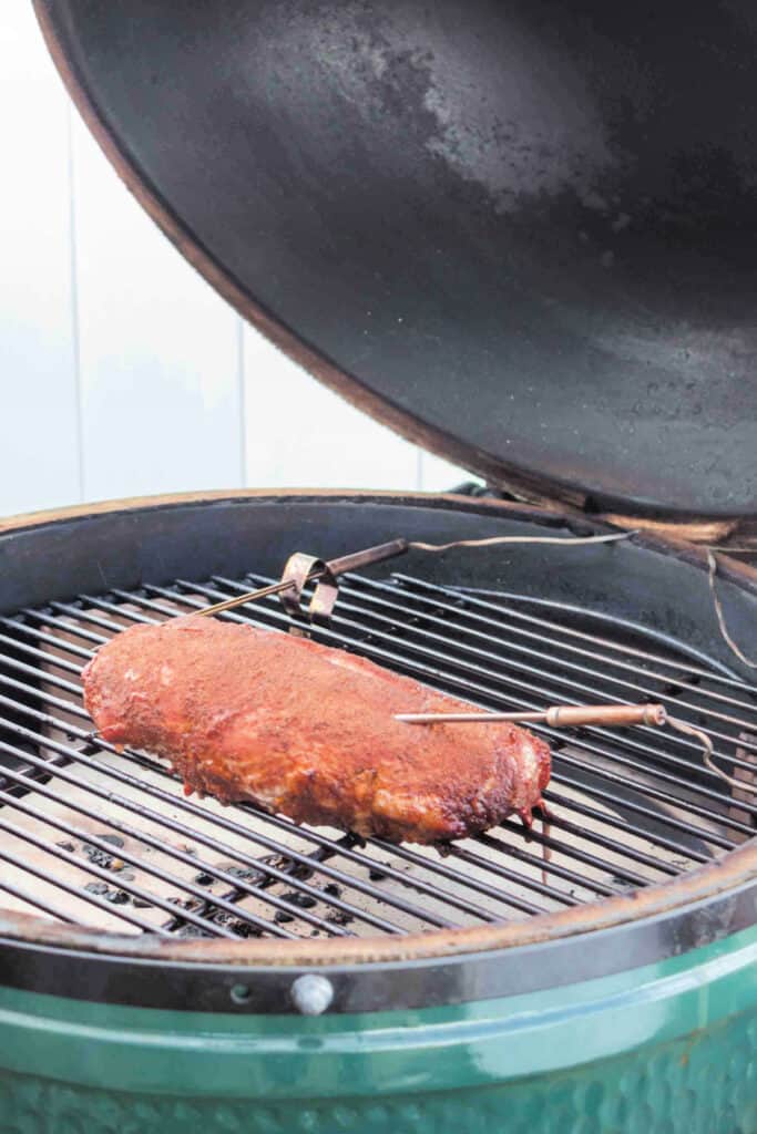 Smoked pork tenderloin halfway through cooking on a ceramic grill