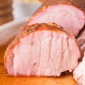 Square close-up of sliced smoked pork tenderloin showing juicy pink interior and spice-rubbed crust