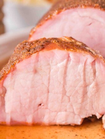 Square close-up of sliced smoked pork tenderloin showing juicy pink interior and spice-rubbed crust