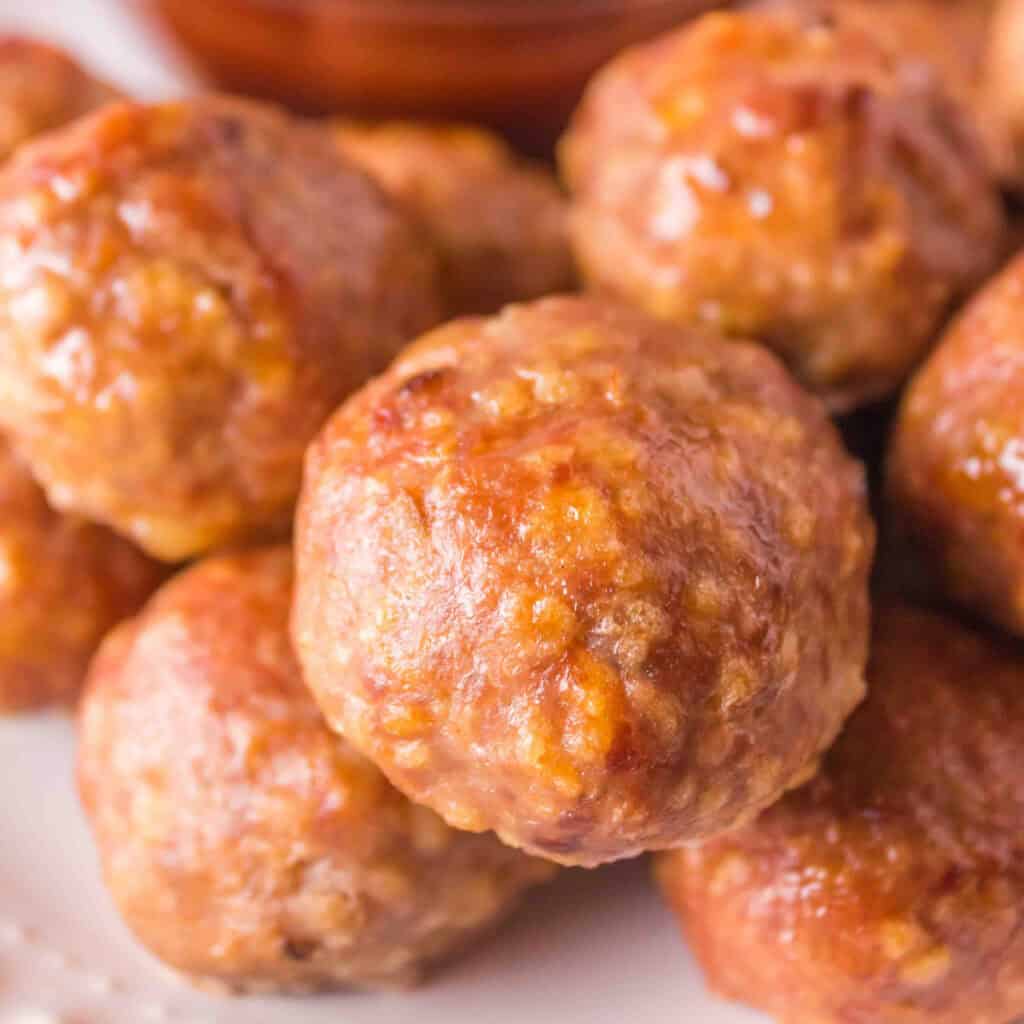Square-cropped close-up of smoked turkey meatballs served with BBQ sauce.