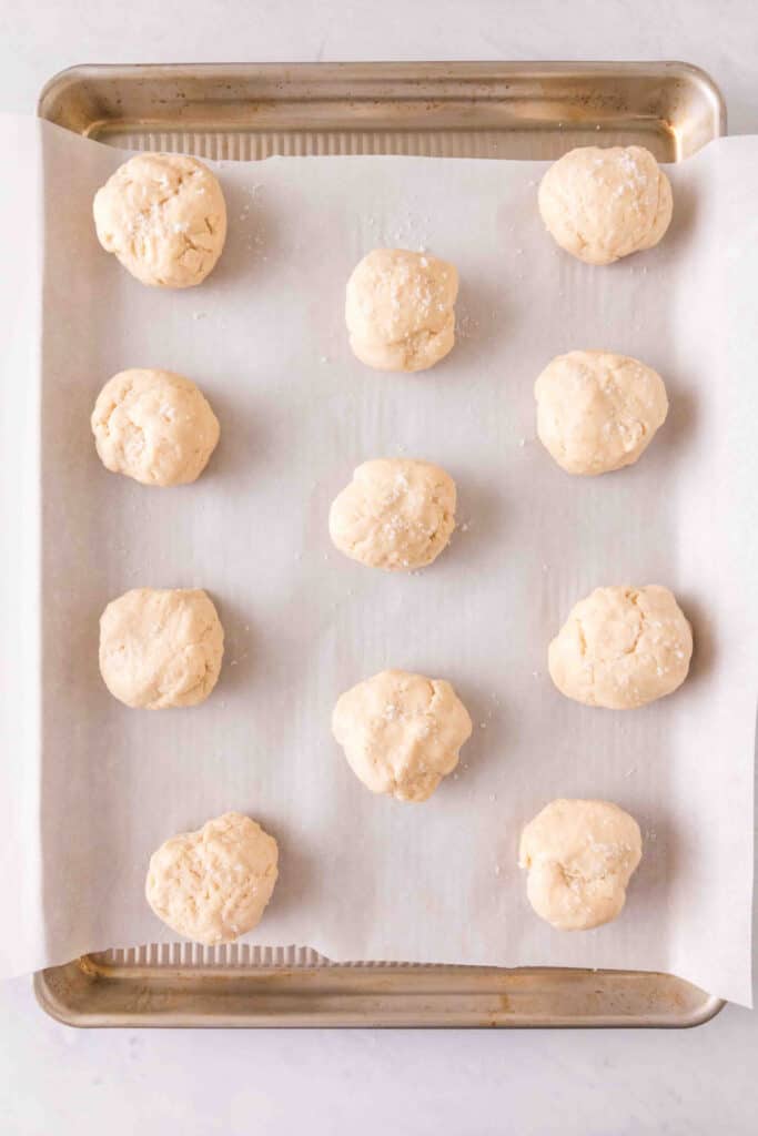 Raw scone dough balls arranged on a parchment-lined baking sheet