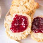Overhead square crop of scones topped with butter and jam