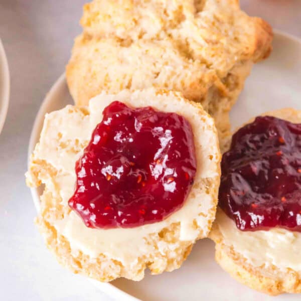 Overhead square crop of scones topped with butter and jam