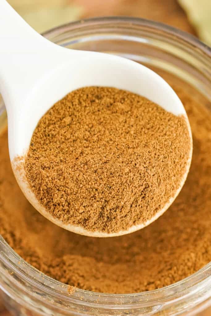 Close-up of a heaping spoonful of apple pie spice over a glass jar