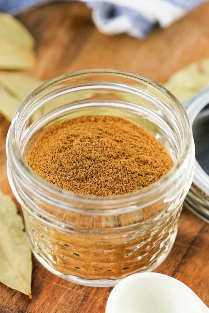 Small mason jar filled with apple pie spice on a wooden surface