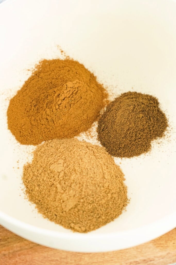 Three mounds of ground spices in a white mixing bowl