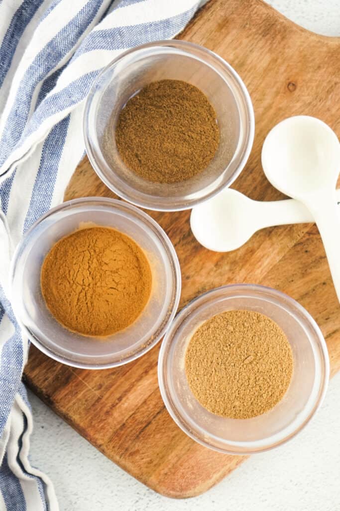 Overhead view of cinnamon, nutmeg, and allspice in small clear bowls