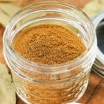 Square-cropped image of homemade apple pie spice in a small glass jar