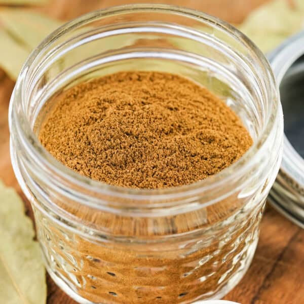 Square-cropped image of homemade apple pie spice in a small glass jar