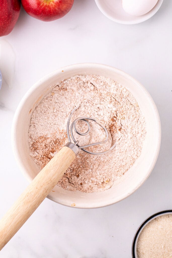 Flour and spices fully mixed together in a bowl with a Danish dough whisk