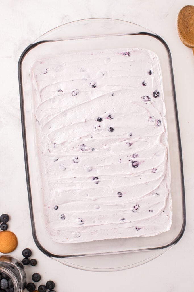 Smoothly layered blueberry cheesecake filling in the baking dish, ready for next layer