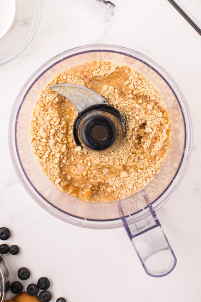 Crushed cookie mixture combined with melted butter inside food processor
