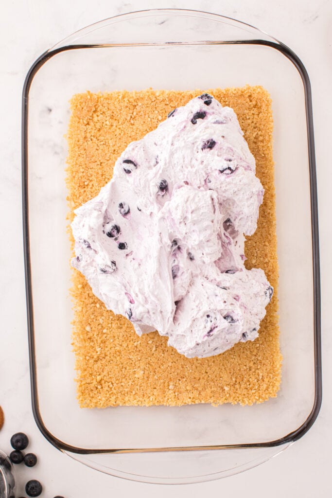 Blueberry cheesecake mixture spread on top of cookie crust in baking dish