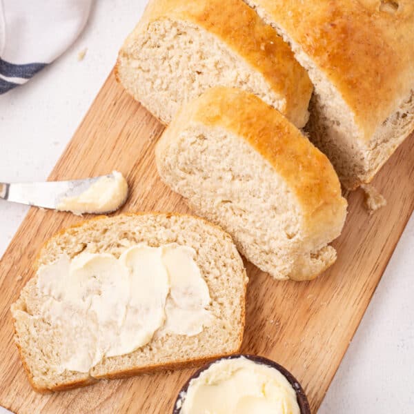 Overhead shot of sliced bread with butter on a board with a butter knife