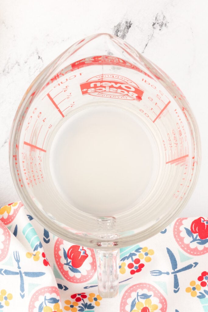 Overhead view of lemon juice at the bottom of a glass measuring cup.
