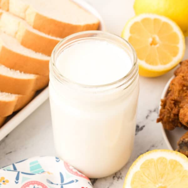 Jar of buttermilk substitute with bread, lemons, and fried chicken.