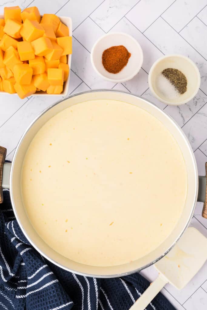 Smooth, creamy soup base simmering in the pot with Velveeta cubes and seasonings nearby, ready to be added.