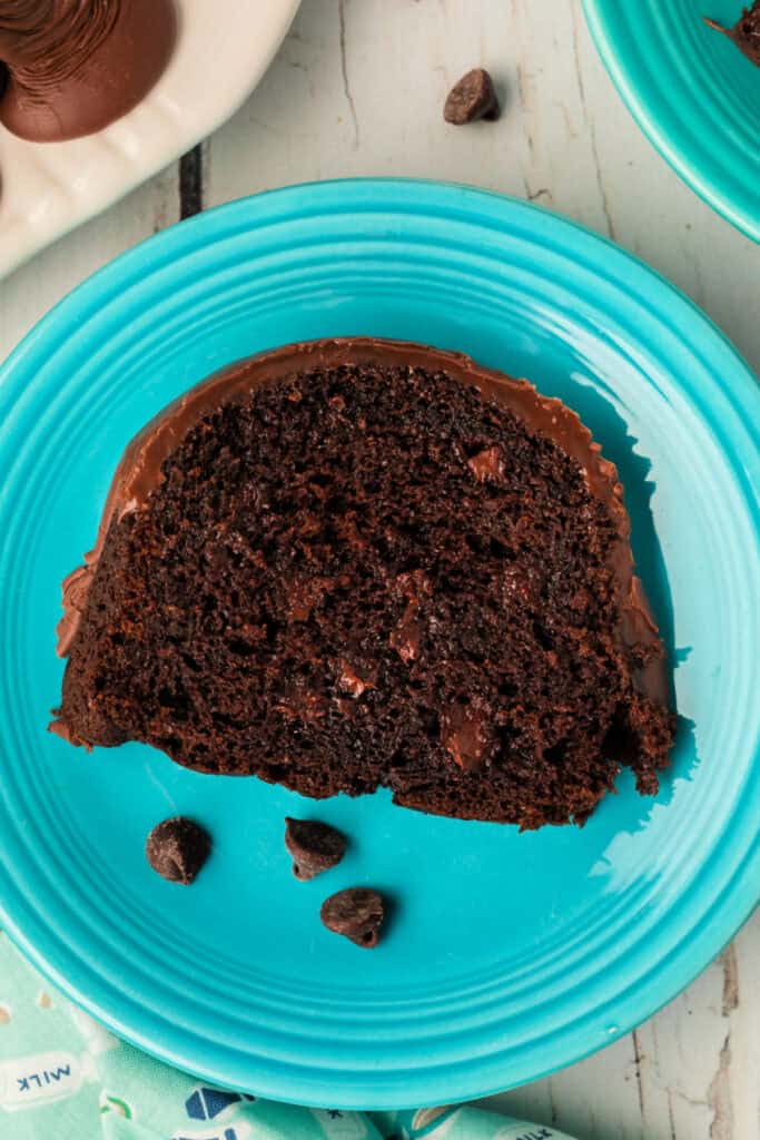 Close-up of a slice of Death by Chocolate Bundt Cake on a turquoise plate, showing the moist chocolate crumb and melty chocolate chips.