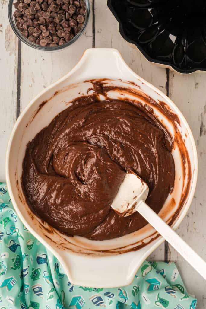 Thick chocolate cake batter fully mixed in a white mixing bowl with a spatula resting on the side.