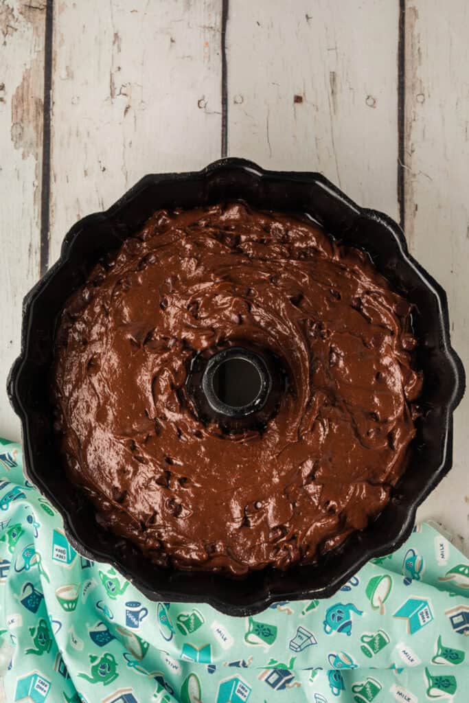 Chocolate cake batter spread evenly in a greased Bundt pan, ready for baking.
