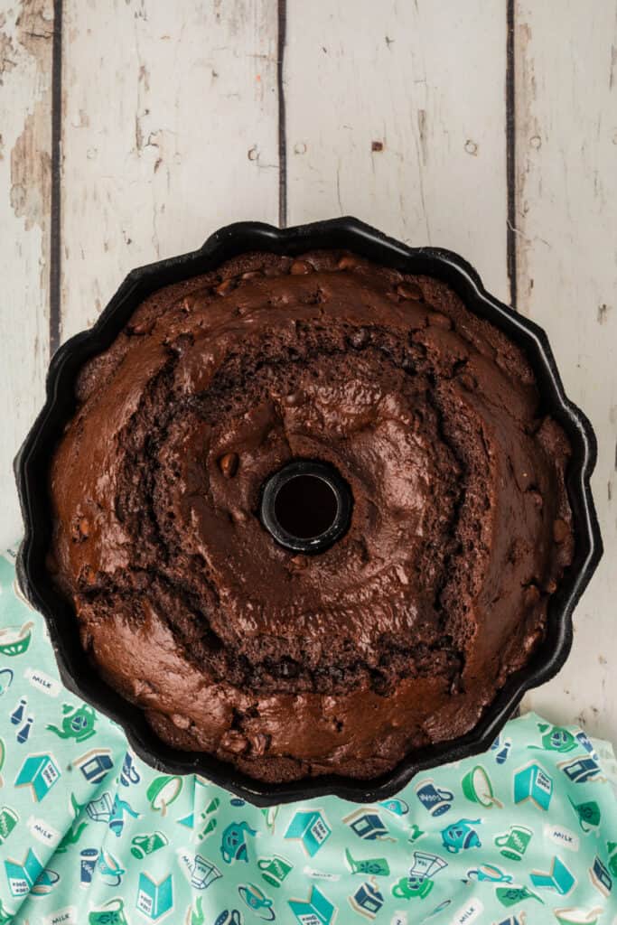 	Freshly baked chocolate Bundt cake in the pan, fully risen with visible chocolate chips on the surface.