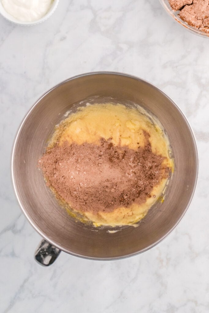 Dry ingredients being mixed into the wet batter in the stand mixer bowl.