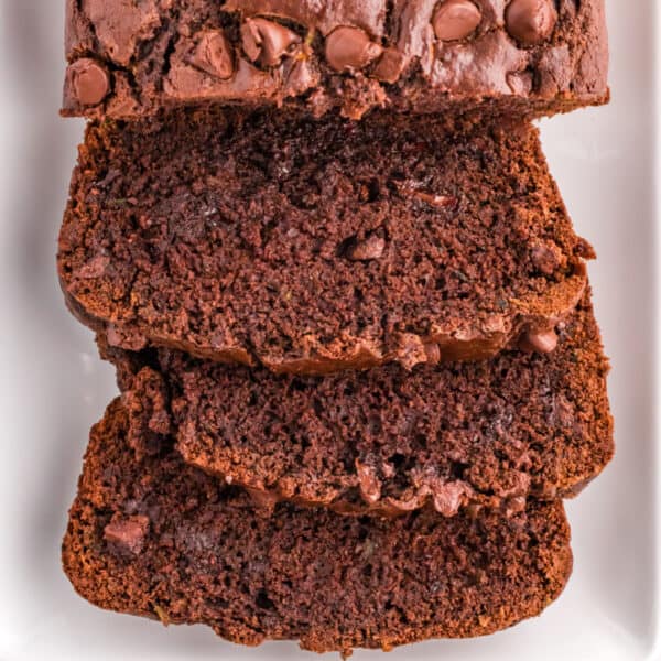 Cropped square image of sliced double chocolate zucchini bread showing gooey chocolate chips inside.