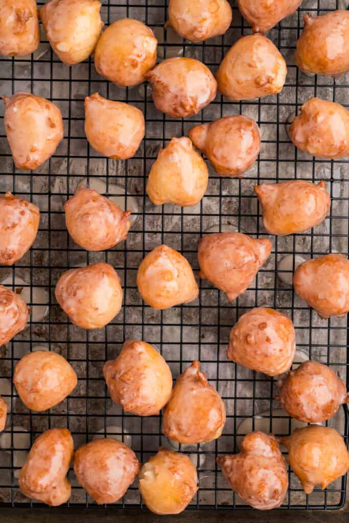 Glazed donut holes drying on a cooling rack