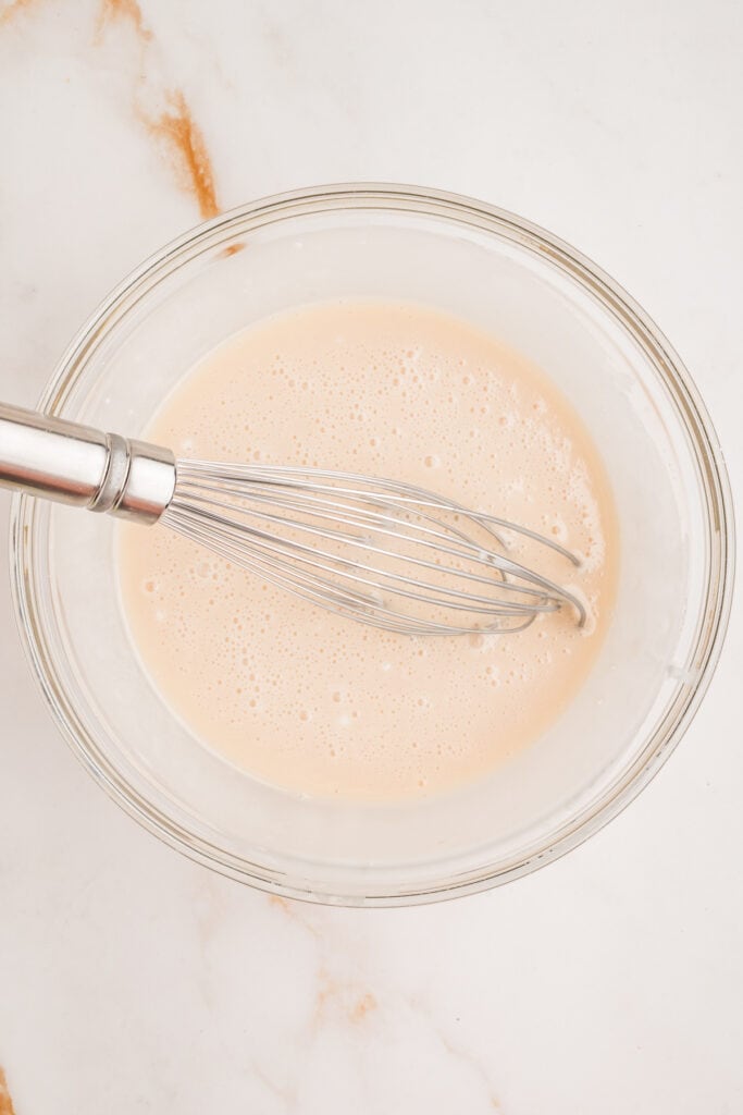 Smooth vanilla glaze whisked in a glass bowl with a metal whisk