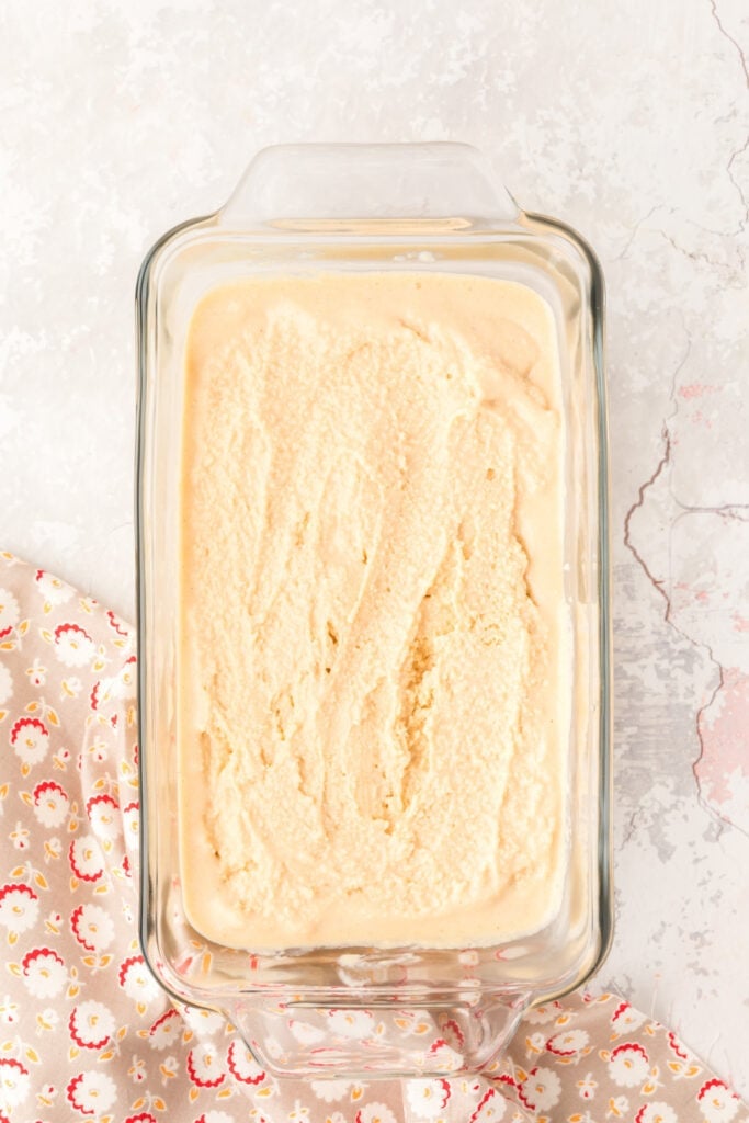 Churned peanut butter ice cream spread evenly in a glass loaf pan.