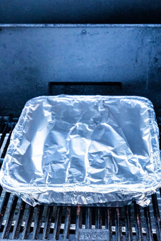 Foil pan tightly covered with aluminum foil on the smoker.