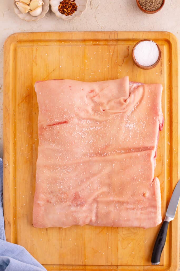 Pork belly on a cutting board lightly salted and ready to prep