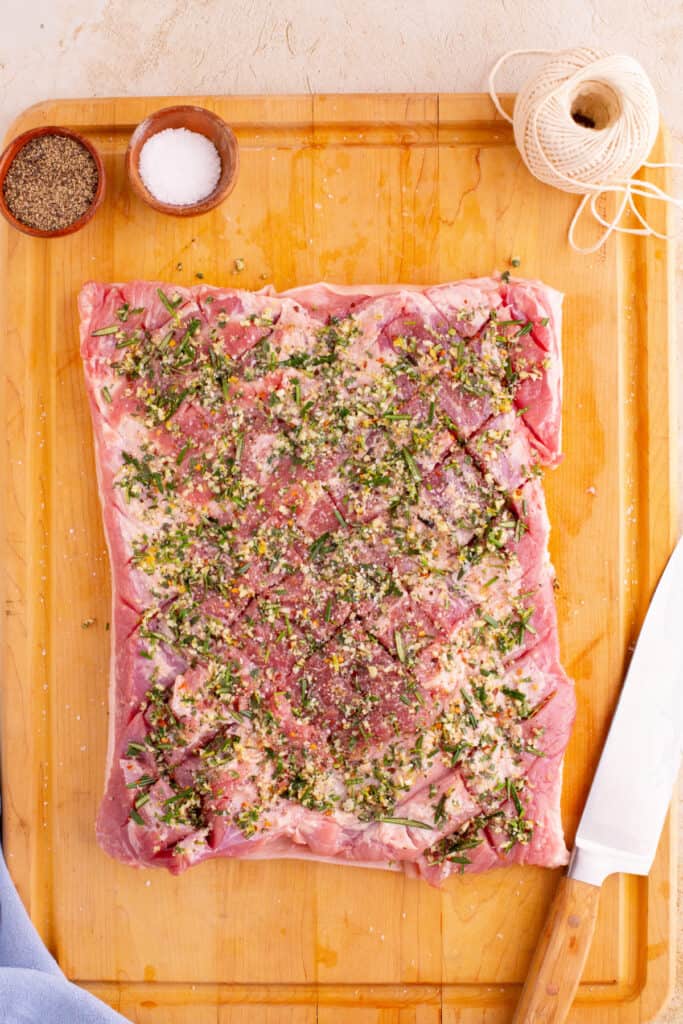 Pork belly with herb mixture spread evenly across the scored meat surface