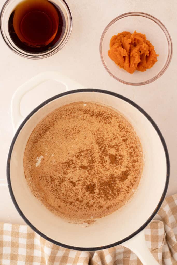 Pumpkin puree and maple syrup next to saucepan with heated spices
