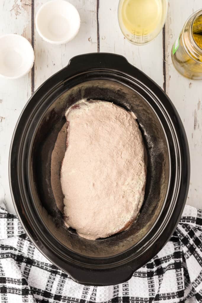 Chuck roast topped with dry ranch and gravy seasoning mixes in the slow cooker