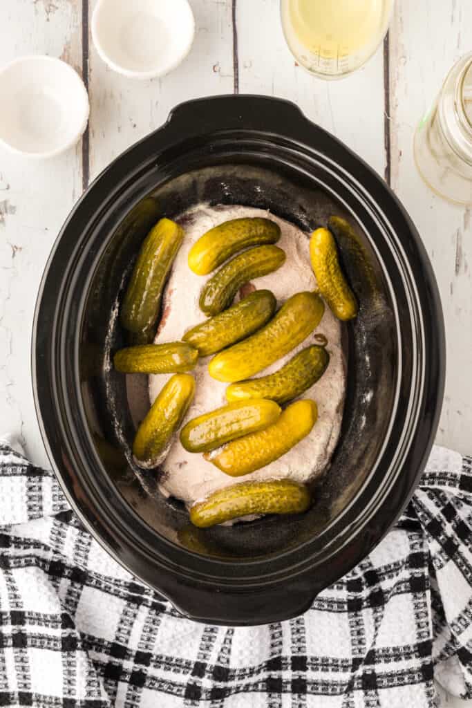 Baby dill pickles added on top of the seasoned roast in the slow cooker