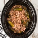 Overhead shot of slow cooker filled with shredded dill pickle pot roast and baby dill pickles