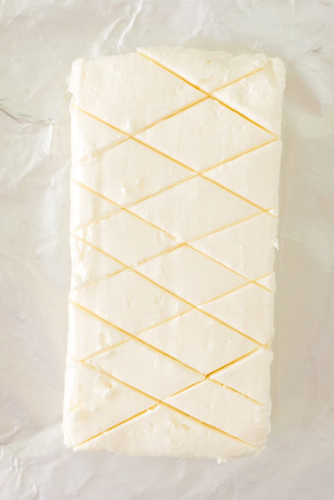 Cream cheese block scored in a crisscross pattern on foil