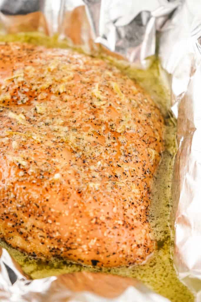 Smoked turkey breast in foil after being cooked, sitting in melted herb butter